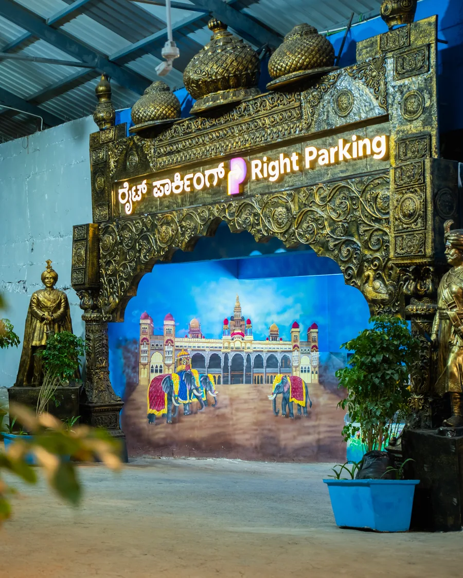 Right Parking at KR Market — ornate gilded entrance archway with bilingual signage, flanking statues and a painted Mysore Palace mural